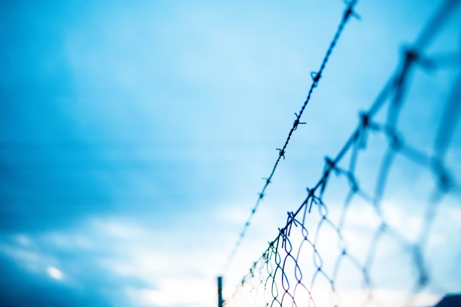 Barbed wire fence in front of a blue sky
