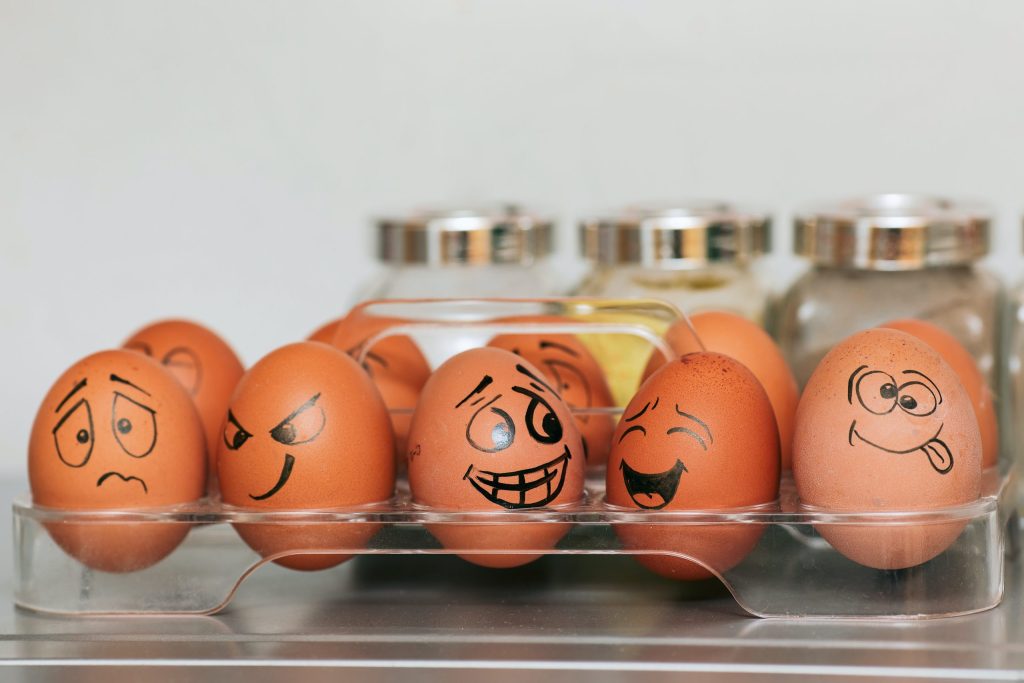 A box of eggs with a range of expressions drawn on
