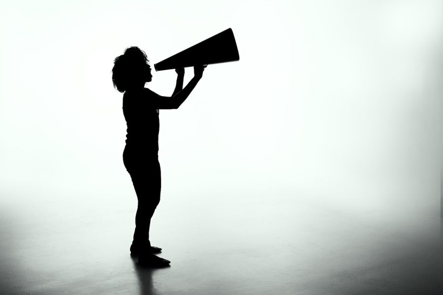 A silhouetted person, shouting into a megaphone