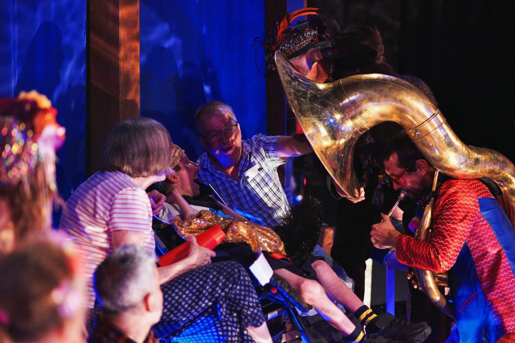 A family interact with a sousaphone player, feeling the vibrations from the instrument