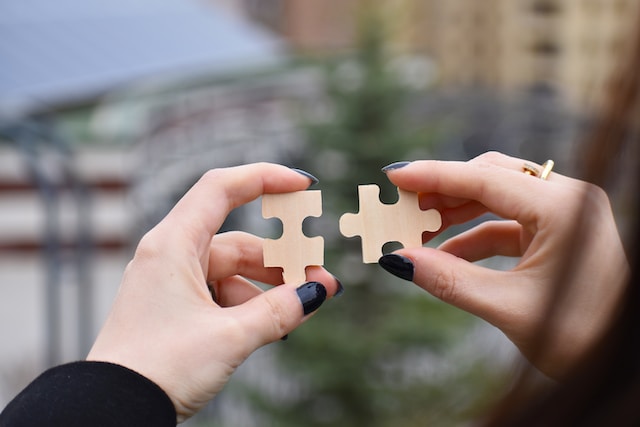 A woman's hands holding two pieces of a jigsaw puzzle
