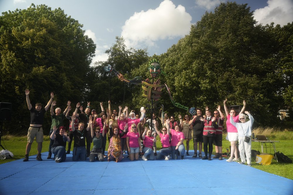 A group of people with their arms raised in a park with sculpture behind | RUOS Evaluation Case Study
