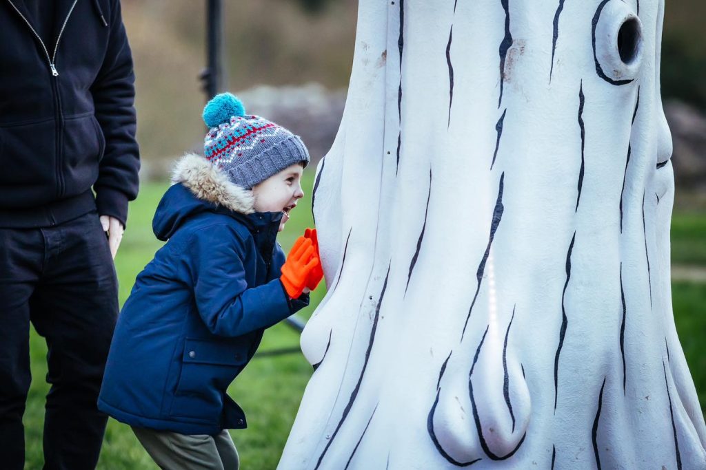 A young child peering happily into a tree sculpture | RUOS Evaluation Case Study