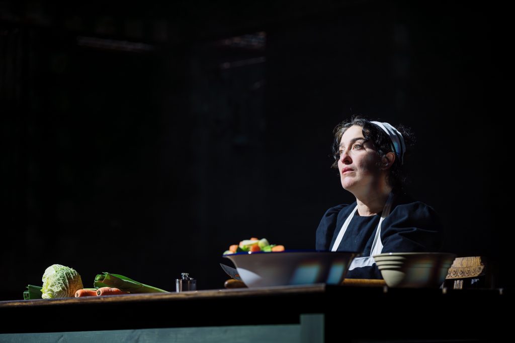 A photograph of a person at a worktop with vegetables. The photograph is taken from CPT's production of Wuthering Heights.