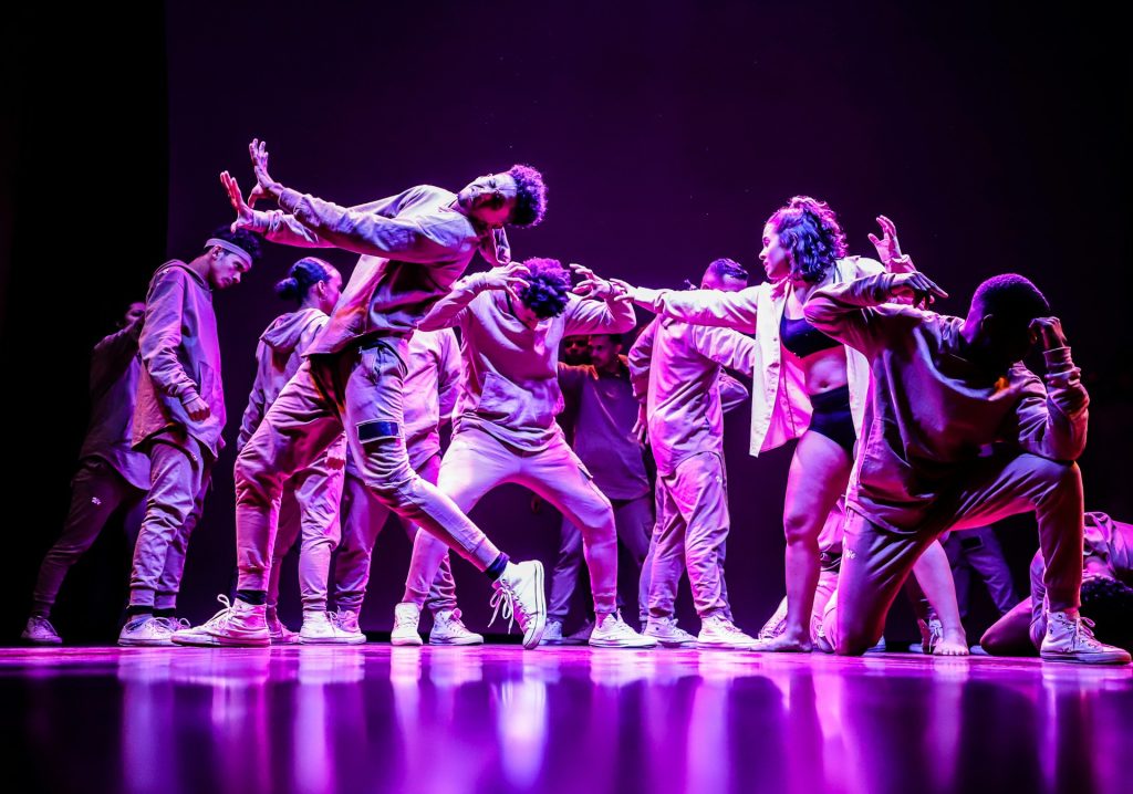 A collection of young adults lit in purple on a stage