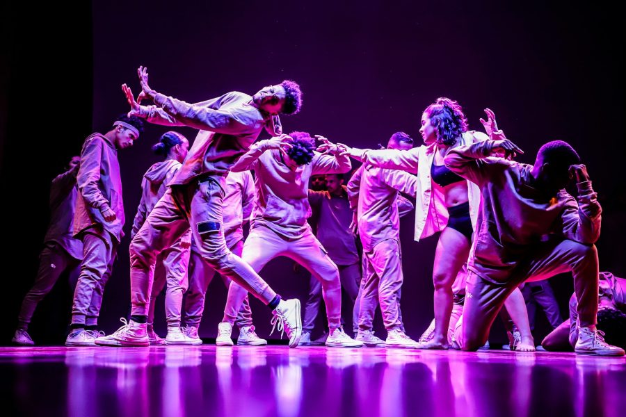 A collection of young adults lit in purple on a stage