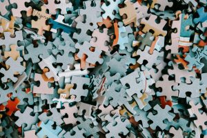 A photograph of an unmade jigsaw featuring hundreds of loose multicoloured abstract jigsaw pieces