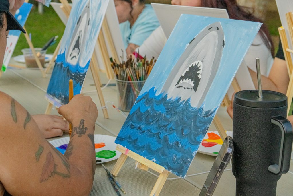 An adult art class painting sharks