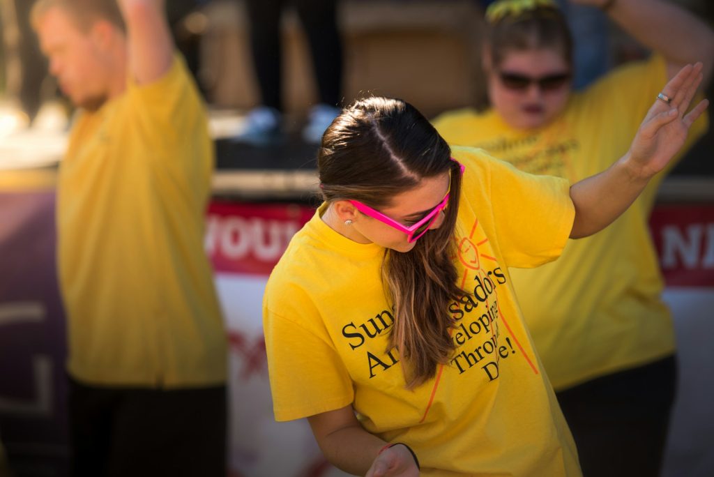 Three people in yellow t-shirts relaxing and moving their bodies