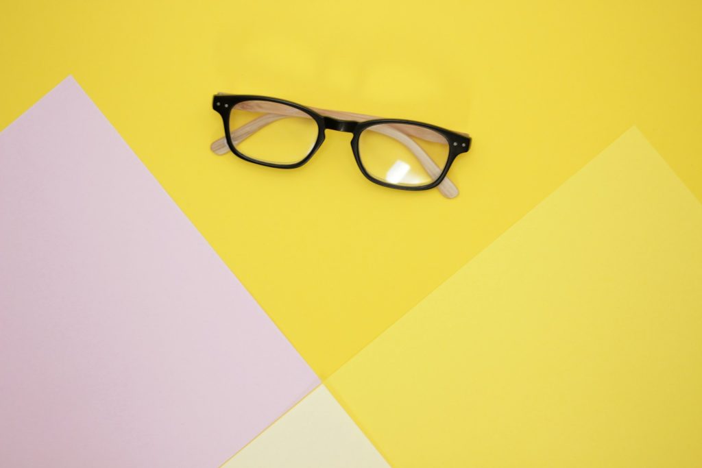 Yellow and pink overlapping papers with a pair of glasses