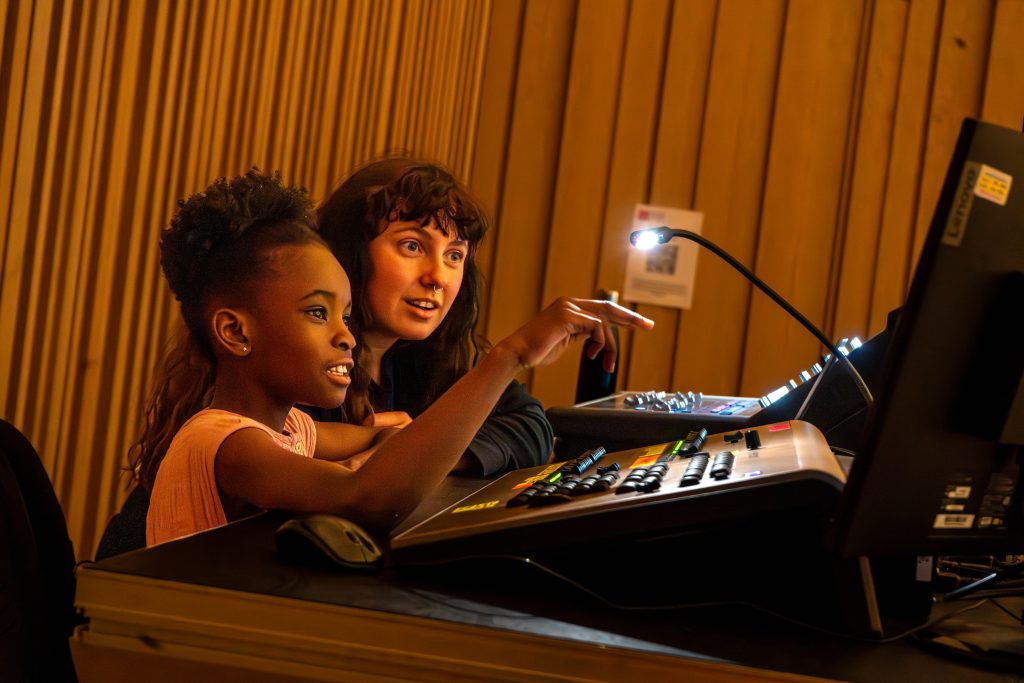A teacher and child working together at a sound desk