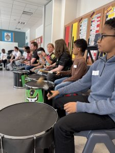 A classroom of children learning to play the drums