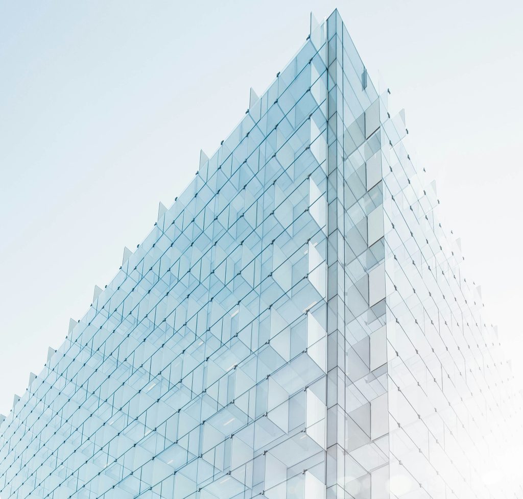 Photo of a triangular glass geometric structure against a pale blue sky