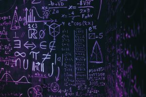 A dark background with mathematical equations written across it in white